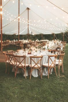 an outdoor tent with tables and chairs set up for dinner