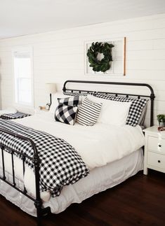 a bed with black and white plaid pillows on top of it in a bedroom next to a window