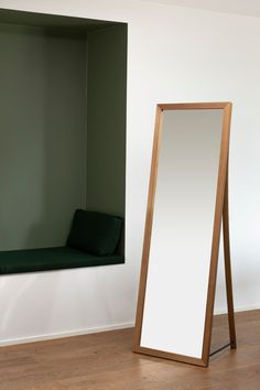 a large mirror sitting on top of a hard wood floor next to a green couch