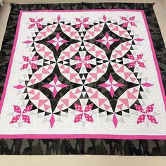 a pink and black quilt is on the floor next to a white table topper