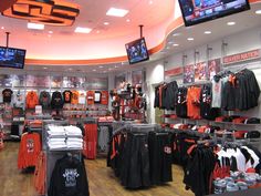 the inside of a sports shop with orange and black jerseys on display in front of televisions