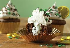 three cupcakes with white frosting and green sprinkles on top