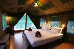 a large bed sitting inside of a tent next to a wooden table and chair with two stuffed animals on top of it