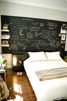 a bedroom with a chalkboard wall behind the bed