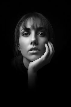 a black and white photo of a woman with her hand on her chin looking at the camera