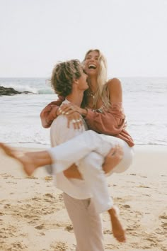 a man carrying a woman on his back at the beach