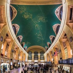 the inside of an indoor train station with people walking around and looking up at it