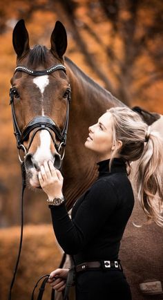 a woman is holding the bridle of a brown and white horse as it stands next to her