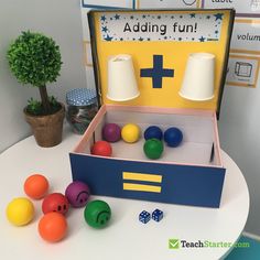 an open box filled with balls sitting on top of a table next to a potted plant