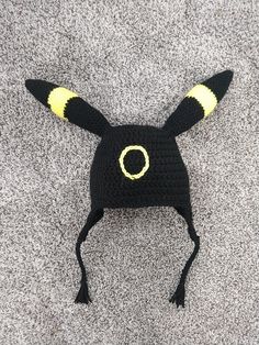 a crocheted hat with yellow horns on the front and black ears is laying on a gray surface