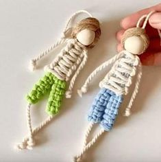 two knitted dolls are being held by someone's hand