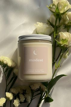 a candle and some flowers on a white sheet with the word modest written in it