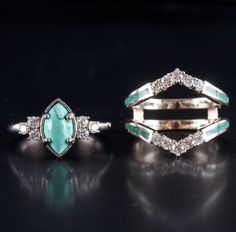 two rings with turquoise stones and diamonds on black surface, one is in the shape of an arrow