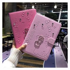 two hello kitty notebooks are being held up