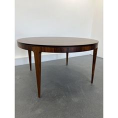 a wooden table sitting on top of a cement floor next to a white walled wall