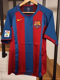 a red and blue soccer jersey hanging on a rack