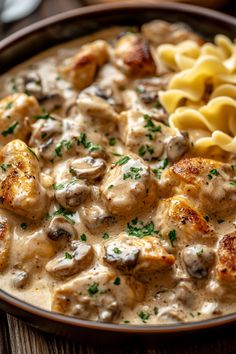 a bowl filled with pasta and meat covered in gravy on top of a wooden table