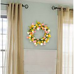 a wreath is hanging on the wall next to curtains