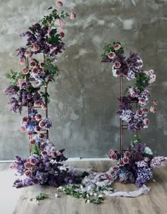 an arrangement of flowers arranged in the shape of two frames on a wooden floor next to a concrete wall