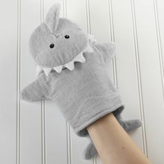 a person's hand wearing a gray mitt with a shark on it