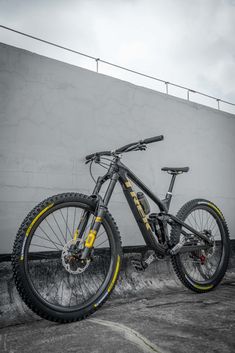 a mountain bike parked in front of a building with graffiti on the side and yellow rims