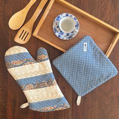 an oven mitt, tea pot and wooden utensils on a wood table