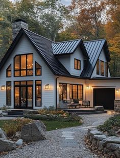 a white house in the woods with lots of windows and lights on it's roof