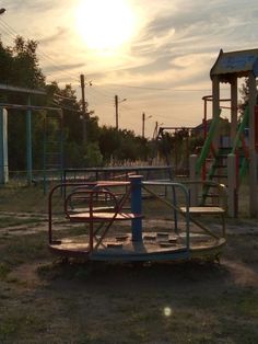 an empty playground with swings and slides in the background at sunset or sunrise, near a park