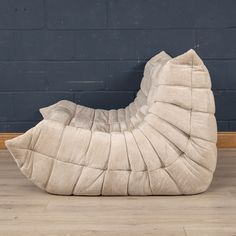 a large white sculpture sitting on top of a wooden floor next to a brick wall