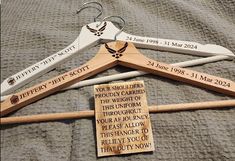 four wooden clothes hangers with names and dates on them, sitting on a bed