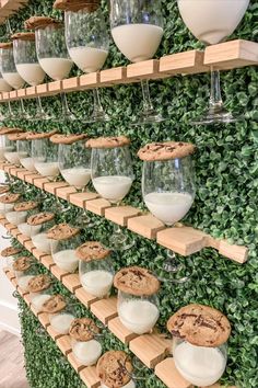 a green wall filled with lots of glasses and cookies on top of wooden shelves next to each other