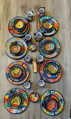 an array of colorful plates and cups are arranged on the floor in order to be displayed