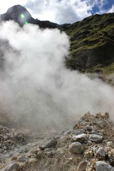 steam rises from the ground in front of a mountain