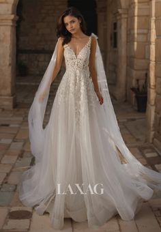 a woman in a wedding dress standing on a stone walkway with her veil blowing in the wind