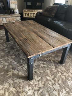 a wooden table sitting on top of a carpeted floor next to a black couch