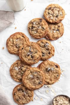 chocolate chip cookies and oatmeal are on the table next to a glass of milk