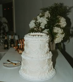 a wedding cake sitting on top of a table next to a vase with white flowers