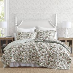 a white bed with floral comforter and pillows