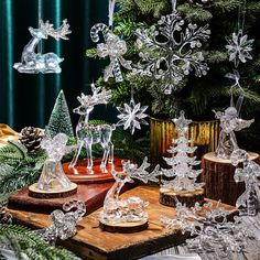 an assortment of glass christmas ornaments on a wooden table with pine cones and fir trees