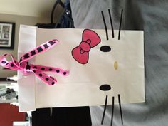 a paper bag with a hello kitty design on the front and pink bow at the top