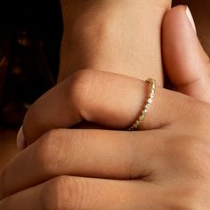 a woman's hand with a gold ring on her left wrist and the other hand holding an engagement ring