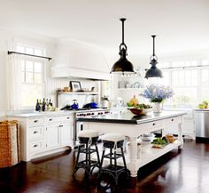 a large kitchen with white cabinets and black counter tops, two stools at the island