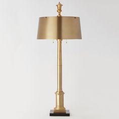 a gold lamp with a black base on a white background