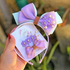 a hand holding up a purple and white minnie mouse ear with pearls on it's ears