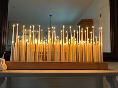 a bunch of lit candles sitting on top of a wooden table in front of a mirror