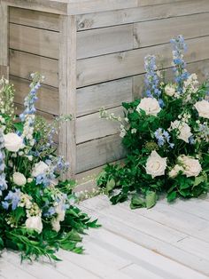 some white and blue flowers are on the floor next to a wooden box with greenery