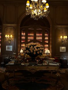 a fancy room with chandelier, bookshelves and flowers on the table