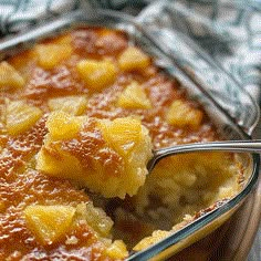 a casserole dish with pineapple topping and a spoon in it, ready to be eaten