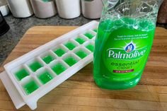 a bottle of palmolive on a cutting board next to an ice tray filled with soap