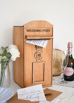 a wooden post box sitting on top of a table next to wine glasses and flowers